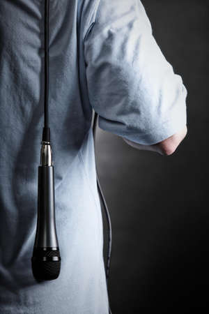 Rear view of male back with microphone. Man resting mic over shoulderの写真素材