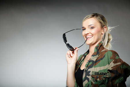 woman in military clothes with sunglasses army girl on gray background.