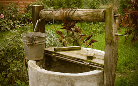 old rotten water well in sumer garden, rural scenery