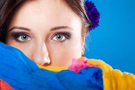 Young woman make up on eyes hides her face with multicolored shawl, veiled girl blue の写真素材