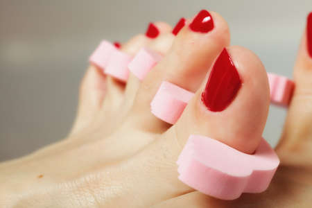 woman's feet with red toenails in toe separatorsの写真素材