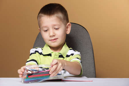 little boy child kid drawing with color pencils on brown backgroundの写真素材