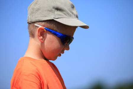 Little boy kid with sunglasses and cap outdoor sky backgroundの写真素材