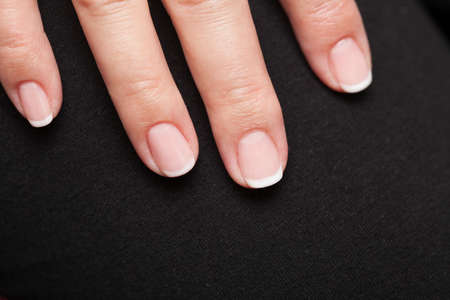 Close-up of woman hand with french manicure part of palm female fingers black background
