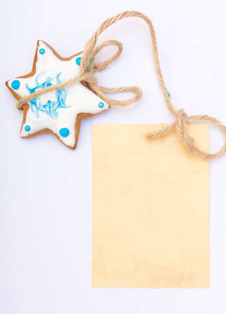 Homemade gingerbread cake star with icing and blue decoration and blank paper card copy-space on white as christmas background  Holiday handmade concept  の写真素材