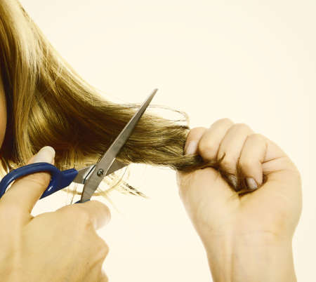 Damaged dry hair splitting ends. Female hands cutting hair with scissors