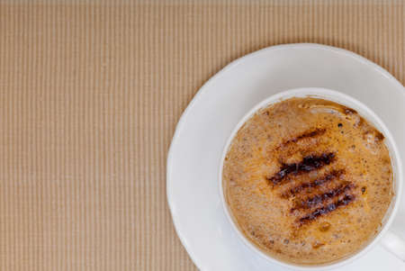 White cup of hot beverage drink coffee cappuccino latte with froth on brown background. Studio shot.の写真素材