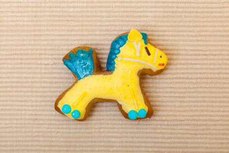 Homemade gingerbread cake pony with icing and blue yellow decoration on brown as christmas background. Holiday handmade concept.の写真素材