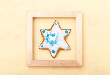 Homemade gingerbread cake star with icing and blue decoration in wooden frame on brown as christmas background. Holiday handmade concept.の写真素材