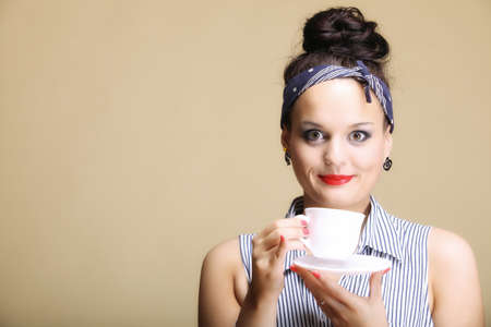 Hot beverage. Woman funny girl holding a cup of tea or coffee copyspace brown backgroundの写真素材