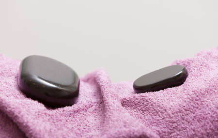 Spa relax body care concept. Zen, hot massage stone pebbles on pink towel. Healthy lifestyle.