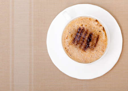 White cup of hot beverage drink coffee cappuccino latte with froth on brown background. Studio shot.の写真素材