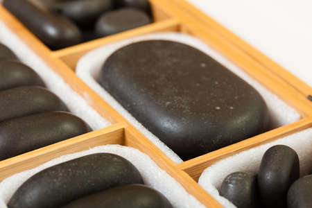 Beauty salon. Close up of black spa zen massage stones in wooden case with white blank copy space for text message. Relax concept.の写真素材