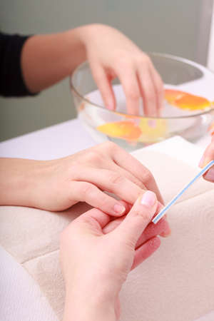 Beautician with file filing nails female client. Woman spa beauty salonの写真素材