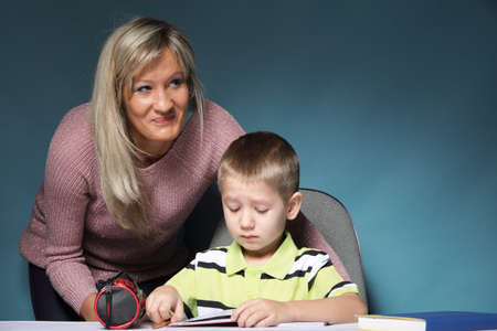 mother and son drawing together, mom helping with homework daycare blue background