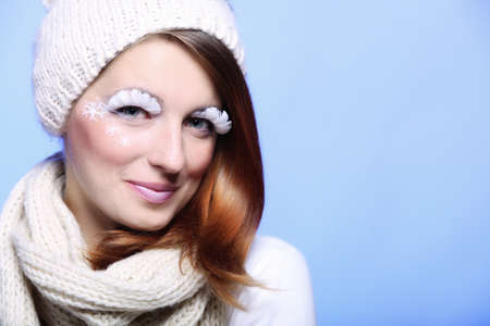 winter fashion beautiful woman in warm clothing stylish creative make up false long white eye lashes blue backgroundの写真素材