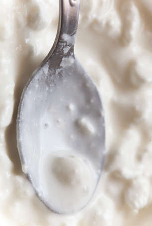 Macro or close-up of white cottage cheese with teaspoon. Diet and healthy nutrition. Studio shot.の写真素材