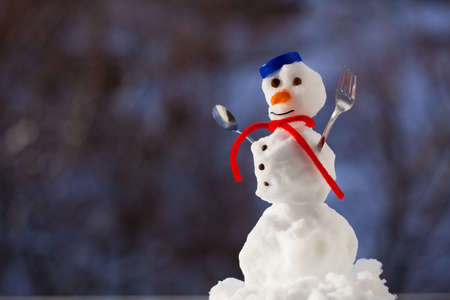 Little happy christmas snowman in blue screw top as hat red scarf with fork teaspoon outdoor. Winter season seasonal specific. Blurred background.の写真素材