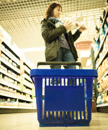 Woman shopping with blue basket at supermarket self-service grocery shop. Retail. Real.の写真素材