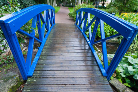 Blue small bridge over river stream creek in green garden. Nature and landscape.の写真素材