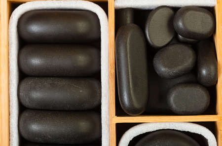 Beauty salon. Close up of black spa zen massage stones in wooden case as background. Relax concept.の写真素材