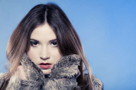 Portrait of fashionable girl with long hair  Young woman in fur coat on blue  Studio shot  Winter fashion の写真素材