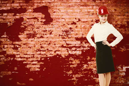 woman architect in red safety helmet on old brick wall