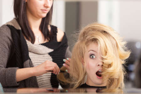 Surprised shocked girl with blond wavy hair by hairdresserの写真素材