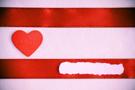 Valentines day background  Red satin ribbon with wooden heart on pink cloth  Copy space for textの写真素材