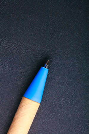 Blue pen ballpoint writing material on black leather background. Blank copy space. Business or education object.の写真素材