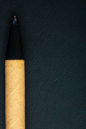 Black pen ballpoint writing material on leather background. Blank copy space. Business or education object.の写真素材