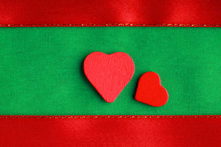 Valentine's day or wedding. Red wooden decorative hearts love symbol on green cloth textile with ribbon background blank copy spaceの写真素材