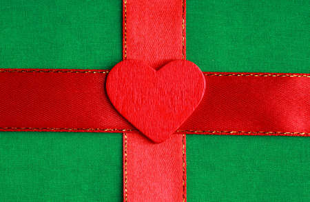Valentine's day. Red wooden decorative heart love symbol on green cloth textile background with ribbon. Blank copy spaceの写真素材