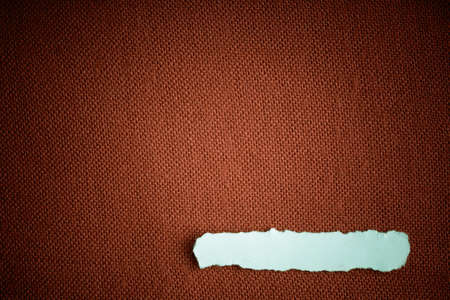 Piece scrap of white paper blank copy space on brown fabric textile material backgroundの写真素材