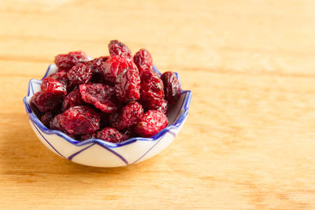 Healthy food organic nutrition. Dried cranberries cranberry fruit in bowl on wooden table backgroundの写真素材