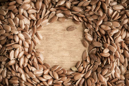 Healthy diet organic nutrition. Brown raw flax seeds linseed border frame on wooden table backgroundの写真素材