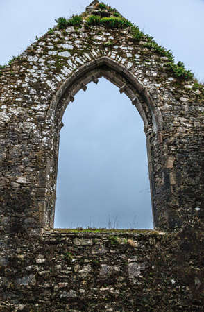 Arch window of old stone fortress or church abbey and sky. Architecture detail.