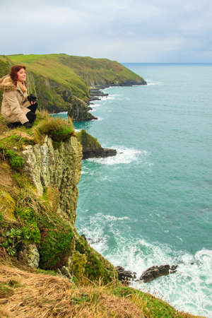 Woman sitting on rock cliff watching the ocean looking to sea  Co  Cork Ireland Europeの写真素材