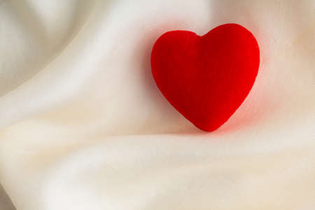 Valentine s day Red decorative heart on abstract white wavy folds cloth or textile elegant materialの写真素材