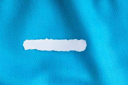 Blank copy space scrap of paper on blue background cloth wavy folds of textile texture material