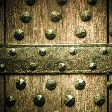 Vintage grunge wooden door gate of the old castle detail with metal rivets. Square format