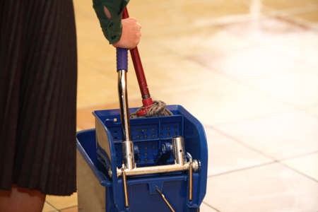 Blue bucket and mop on the tiled floor