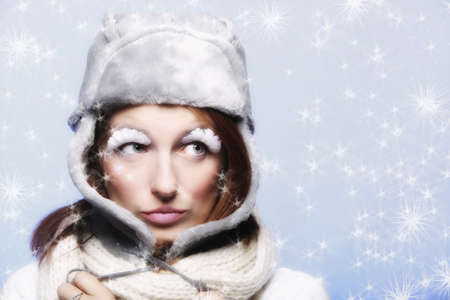 Fashion woman girl in warm clothing fur hat stylish creative make up false long white eye lashes on blue winter snow flakes の写真素材