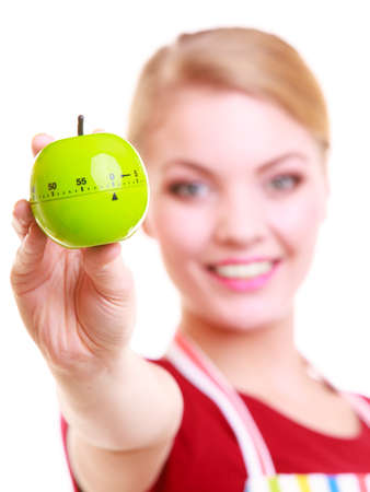 Happy housewife or chef in colorful kitchen showing apple timer eggtimer isolated studio shotの写真素材