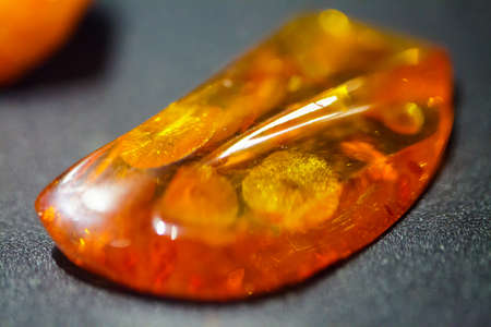 Macro  Closeup of amber golden mineral on grey gray Resin gem 