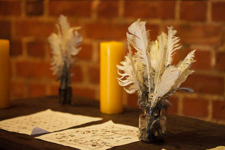 Writing. Feather quill pens, candle and old sheet of paper on wooden desk. Vintage retro style.の写真素材