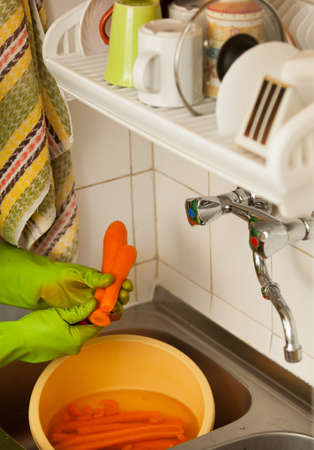 Woman hands in green gloves slicing preparing carrots in kitchen, indoor  Healthy diet, organic nutrition  Realistic, natural image の写真素材
