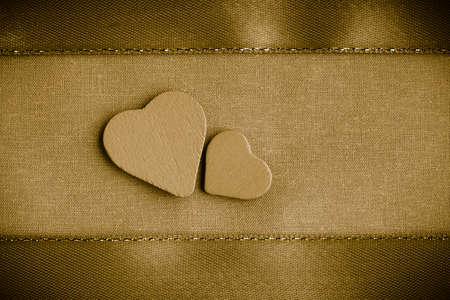 Valentines day or wedding  Wooden decorative hearts love symbol on golden gold beige cloth textile with ribbon background blank copy spaceの写真素材