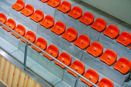 Closeup of red sport stadium seats. Empty stand. Team sport and football supporters fans.