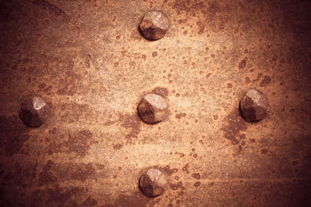 Brown grunge metal plate or armour texture with rivets as backgroundの写真素材